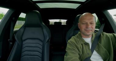 A man drinks from a bottle when driving a car. Front view from the car interior. photo