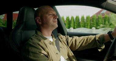 A man drinks from a bottle while driving a car. View from the car interior. Warm summer day photo