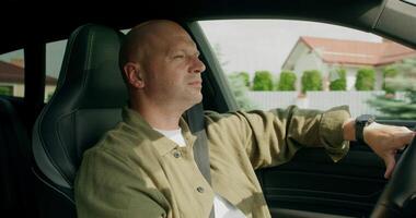 A man wearing a seat belt drives a car with a calm look. View from the car interior. Summer photo