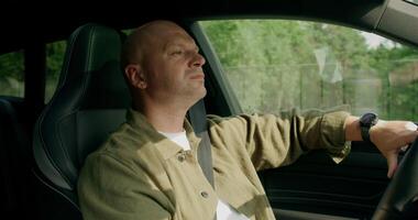A man drinks from a bottle while driving a car. photo