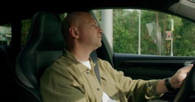 A man wearing a seat belt drives a car with a calm look. View from the car interior. photo