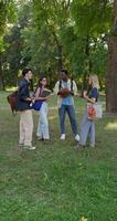 A group of students are talking and smiling while standing in a city park during recess. photo