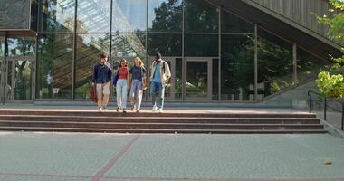 A group of students are talking and smiling as they walk away from the university. S photo