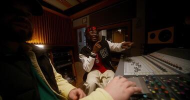 A sound engineer and a singer listen a recorded song sitting in front of an audio mixer. Working in a recording studio photo