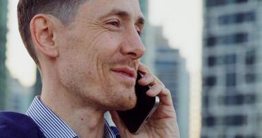 Close-up of a stylish man's face as he talks on a mobile phone while standing on a city street photo