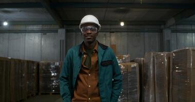 A man in a work uniform is smiling at the camera. He is in the factory warehouse. photo