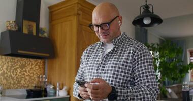 A man with earbuds in his ears is talking on a mobile phone. He holds the phone in his hands. photo