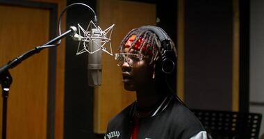 A stylish young man dances while recording rap in a studio photo