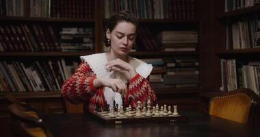 A woman of European appearance plays a chess game alone, thinking long concentratedly between moves photo