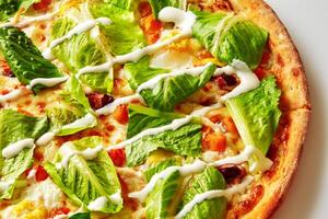 Delicious pizza with lettuce and sauce drizzled on top photo
