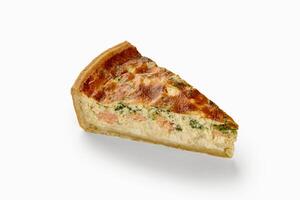 Slice of quiche with salmon and spinach filling on white background photo