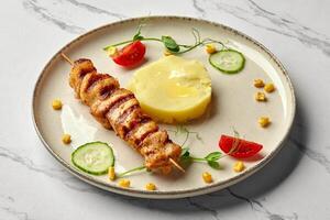 Grilled chicken skewer with mashed potatoes and vegetables on marble table photo