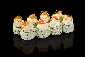 Sushi rolls with cream cheese topping and sesame seeds reflecting on black background photo