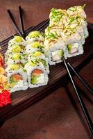 Delicious sushi rolls with chopsticks on wooden board displaying culinary artistry photo