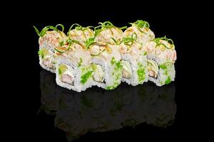 Sushi rolls with shrimp, avocado, cream cheese, and tobiko reflecting on black background photo