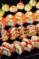 Sushi set displayed on black stone featuring variety of rolls and toppings photo