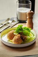 Breaded chicken kiev cutlets served on plate with mashed potatoes, fresh cucumber and lettuce photo