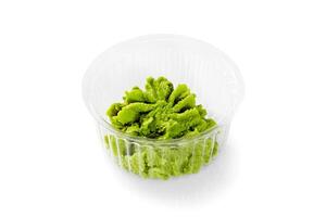 Wasabi paste in plastic container on white background photo
