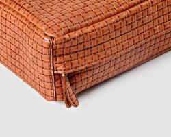 Corner of brown woven leather bag showing zipper detail photo