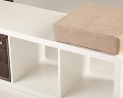 Modern white storage bench with beige cushion and empty compartments photo