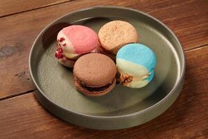 Colorful macarons resting on modern plate on rustic wooden table photo