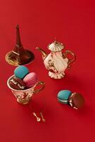French macarons, teapot and eiffel tower on red background representing paris lifestyle photo