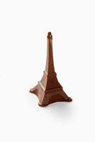 Chocolate eiffel tower sparkling with gold dust on white background photo