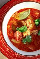 Spicy tom yum soup with shrimp, lime, and cilantro in a bowl photo