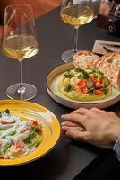 Couple enjoying dinner with wine, caesar salad, and hummus at restaurant photo