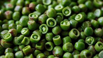 Pile of green peas with some cracked open providing a glimpse of the inside of each pod photo