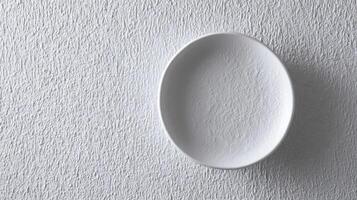 Ceramic white plate on textured surface ideal for minimalistic table settings and modern decor photo