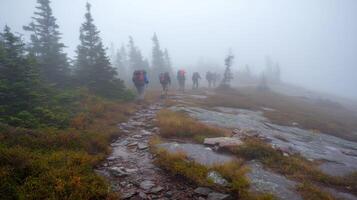 Group of hikers in reflective gear trek along a rocky path through dense fog in the mountains photo