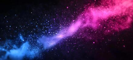 A vibrant explosion of pink and blue dust particles is seen against a black backdrop photo