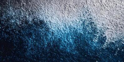 Aerial perspective shows a textured surface transitioning from deep blue to lighter gray photo