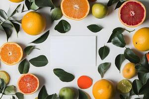 Citrus halves and whole fruit with leaves surround a blank white card from above photo
