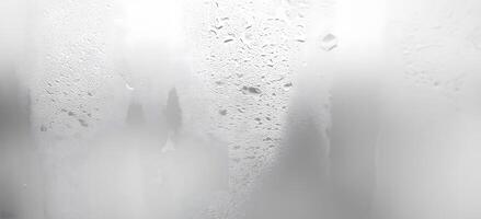 Condensation forms intricate patterns of water droplets across a translucent, textured glass surface photo