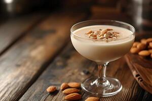 Creamy dessert is topped with chopped almonds and cinnamon served in a glass on wood photo