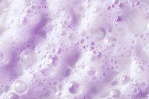 Delicate lilactinted bubbles and foam form a visually captivating, textured surface in closeup photo