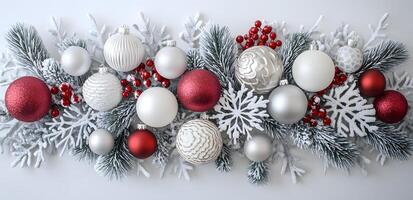 Snowcovered pine branches are interspersed with red and white ornaments against a bright background photo