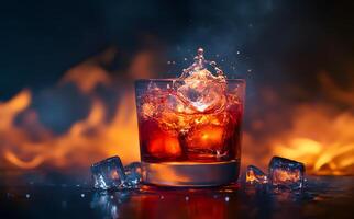 Ice splashes from glass with red liquid sitting on a wet reflective surface with background fire photo