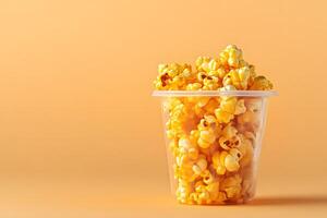 Delicious caramel popcorn fills a clear plastic container against a solid lightorange background photo
