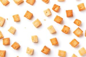 Multiple golden brown croutons are scattered evenly on a bright white surface, simple and plain photo