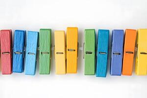 A vibrant row of colorful wooden clothespins are placed in a line on a clean background photo