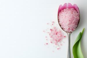 Spoon holds delicate pink salt and fresh tulip petals against clean white background photo