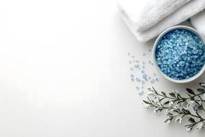 White towels lie by blue bath salts with snowcovered decorative leaves on white photo