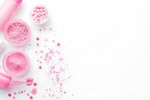Open containers display pink supplements and tablets scattered across a clean white background, providing space photo