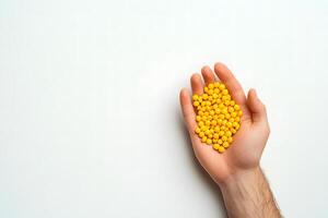 Man holds bright yellow round pills in palm against a clean white backdrop photo