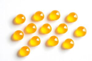Golden translucent gel capsules are arranged neatly on a clean white surface for presentation photo