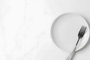 Shiny silver fork is wrapped with measuring tape on a pristine white plate photo