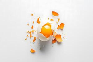 Shiny egg yolk is seen inside a broken shell with orange pieces around photo